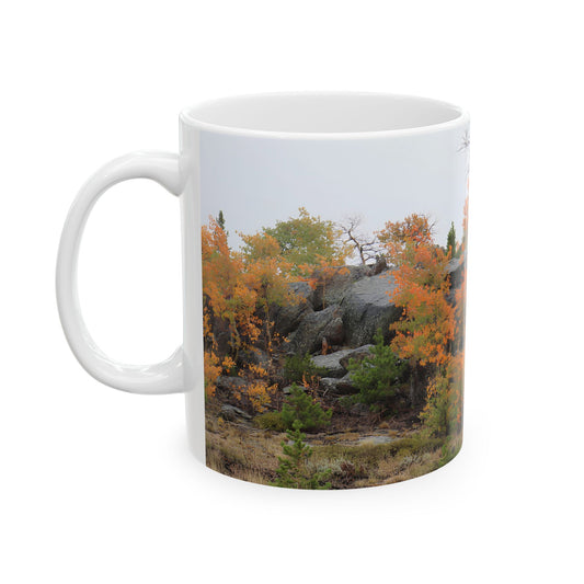 White mug with autumn trees, rocky landscape, and fall foliage print design